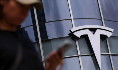 Une femme utilise son téléphone en passant devant un magasin Tesla dans un centre commercial de Pékin