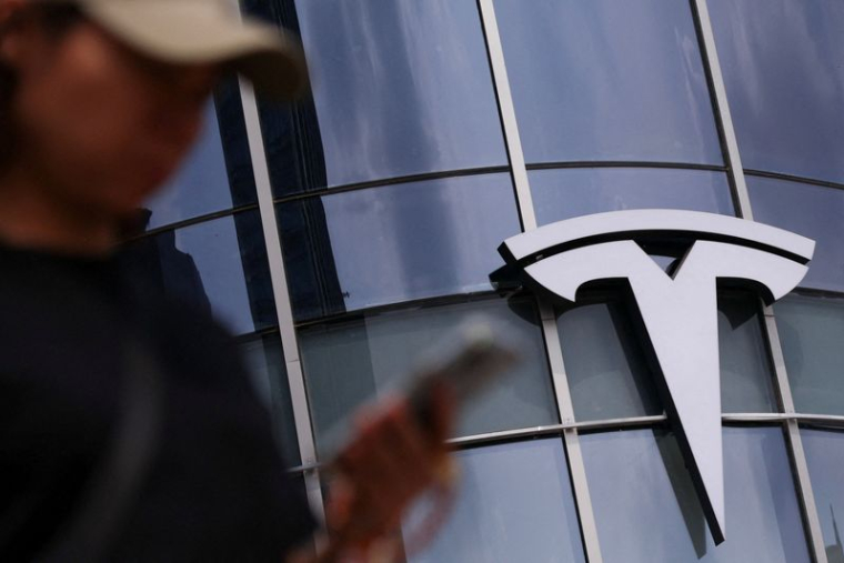 Une femme utilise son téléphone en passant devant un magasin Tesla dans un centre commercial de Pékin