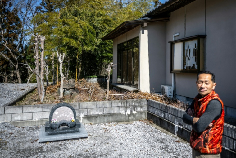 Toru Akama, ancien employé de centrale nucléaire, s'exprime devant le cimetière des animaux de son refuge animalier lors d'un entretien avec l'AFP, à Namie, dans la préfecture de Fukushima, le 5 mars 2026 au Japon ( AFP / Philip FONG )