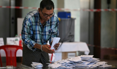 Un membre de la commission électorale birmane (UEC) trie des bulletins dans un bureau de vote de Rangoon, le 28 décembre 2025 ( AFP / Lillian SUWANRUMPHA )