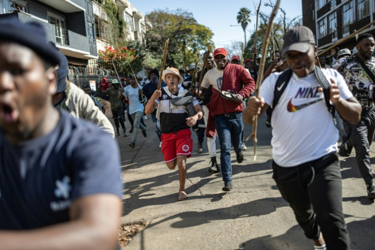 Des manifestants poursuivent des personnes qu'ils pensent être des étrangers en situation irrégulière, lors d'une manifestation organisée par les mouvements March and March et Operation Dudula, le 30 juin 2026à Johannesburg, en Afrique du Sud ( AFP / EMMANUEL CROSET )