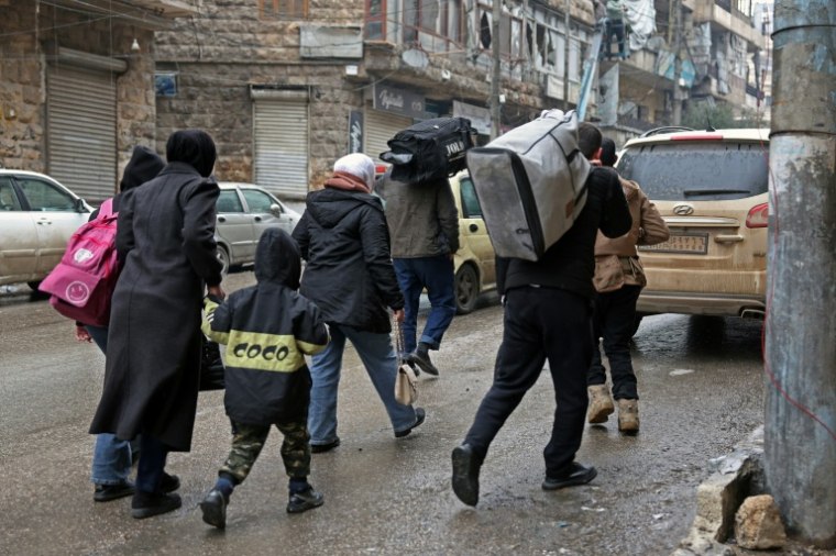 Des habitants déplacés rentrent chez eux après la fin des combats entre forces gouvernementales et kurdes dans le quartier kurde d'Achrafieh à Alep, le 11 janvier 2026 ( AFP / OMAR HAJ KADOUR )