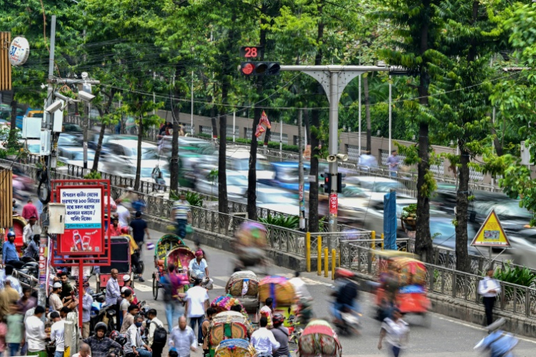 Des automobilistes passent près d'un système de contrôle du trafic basé sur l'intelligence artificielle dans la capitale bangladaise Dacca, le 14 mai 2026   ( AFP / Munir UZ ZAMAN )