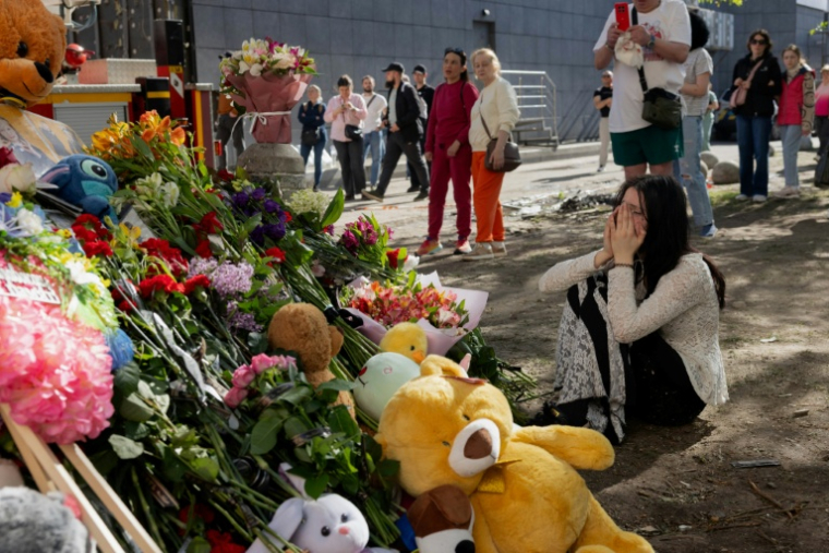 Une jeune femme pleure devant un mémorial improvisé près d'un immeuble résidentiel partiellement détruit à Kyiv, le 15 mai 2026 en Ukraine ( AFP / Tetiana DZHAFAROVA )