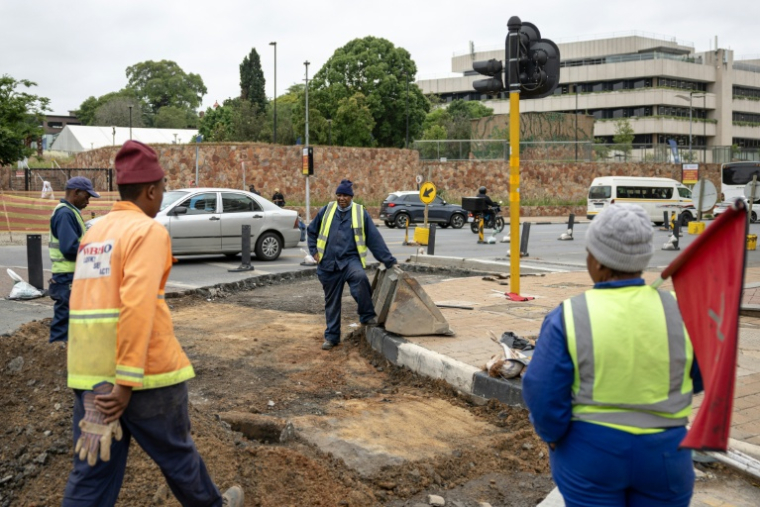 Des ouvriers chargés de l'entretien des routes travaillent dans une rue en cours de rénovation à Braamfontein, Johannesburg, le 7 novembre 2025, alors que la ville se prépare à accueillir le sommet du G20. ( AFP / EMMANUEL CROSET )
