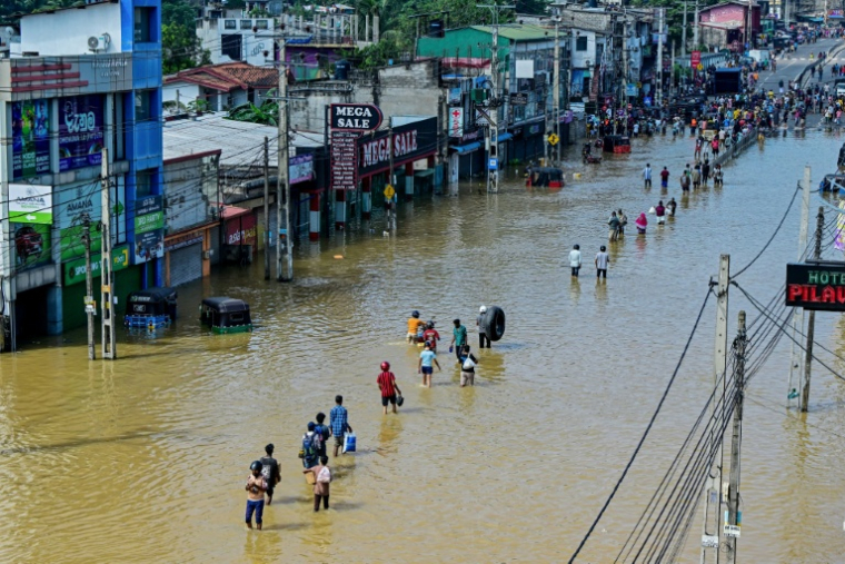 Des personnes traversent une rue inondée après de fortes pluies à Wellampitiya, près de Colombo, au Sri Lanka, le 30 novembre 2025 ( AFP / Ishara S. KODIKARA )