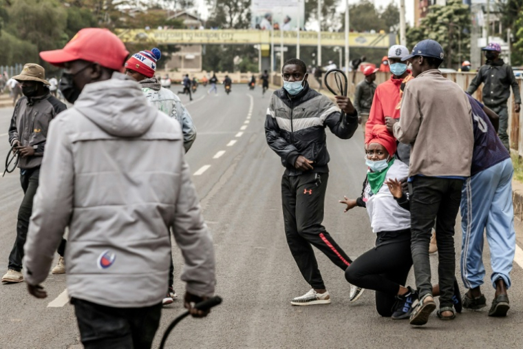 Des hommes armés de fouets et de gourdins bloquent une manifestante, lors d'affrontements à Nairobi, le 17 juin 2025 au Kenya ( AFP / Luis TATO )