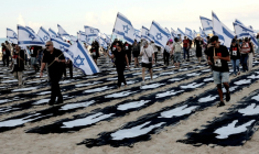 Des personnes portant des drapeaux israéliens traversent une installation commémorative sur la plage de Tel-Aviv pour marquer le troisième anniversaire de l'attaque du Hamas contre Israël, le 7 octobre 2026 ( AFP / Jack GUEZ )