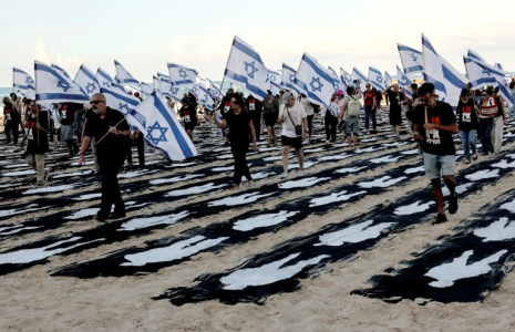 Des personnes portant des drapeaux israéliens traversent une installation commémorative sur la plage de Tel-Aviv pour marquer le troisième anniversaire de l'attaque du Hamas contre Israël, le 7 octobre 2026 ( AFP / Jack GUEZ )