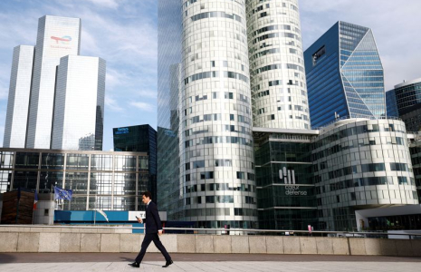 Un homme marche sur l'esplanade de La Défense