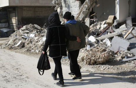 Des gens marchent près des bâtiments endommagés par un tremblement de terre à Jableh, en Syrie