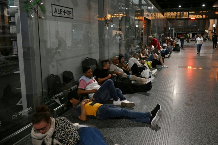 Des voyageurs sont assis ou allongés au sol alors qu'ils se préparent à passer la nuit dans la gare de Cordoue en raison d'une méga-panne électrique affectant l'Espagne et le Portugal le 28 avril 2025 ( AFP / JAVIER SORIANO )