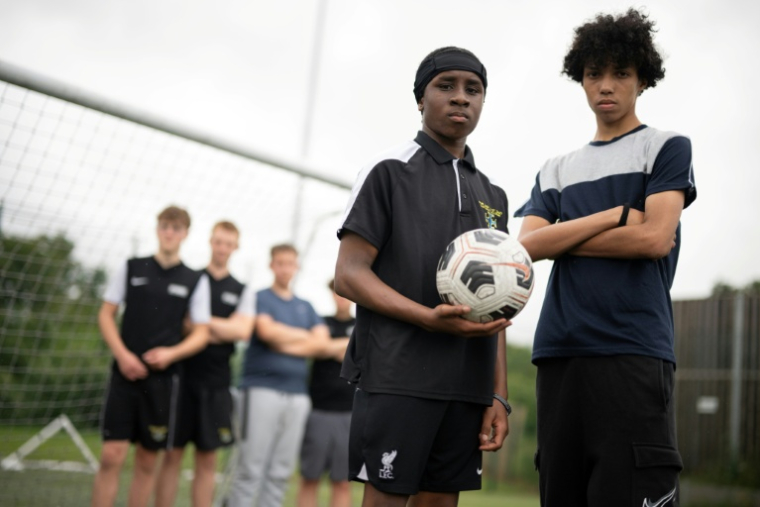 Fabian Myers (r) et Kaziah Cameron (2e d), élèves du collège-lycée public Our Lady and St Chad Catholic Academy et participants du programme "Football Beyond Borders" (FBB), après un match de foot avec d'autres élèves du programme à Wolverhampton, le 12 juin 2026 au Royaume-Uni ( AFP / Oli SCARFF )