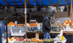 Photo d'une personne qui passe devant un étal vendant des fruits et légumes à Manhattan