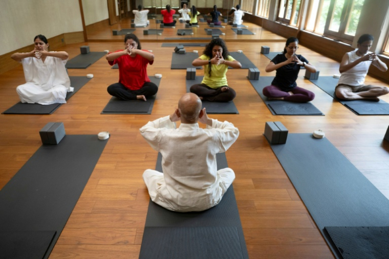 Varun Veer (c), fondateur de Lifeyoga, fait une démonstration de "Pranayama" lors d'une séance dans son studio de New Delhi, le 19 juin 2026 en Inde ( AFP / Arun SANKAR )