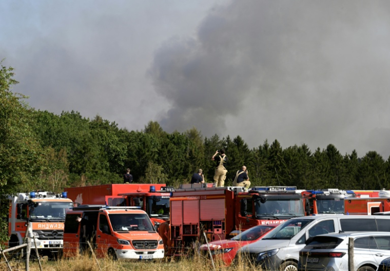 Des pompiers, debout sur le toit de leurs camions, observent un incendie de forêt à Huertgenwald, dans l'ouest de l'Allemagne, le 14 août 2026 ( AFP / Roberto Pfeil )