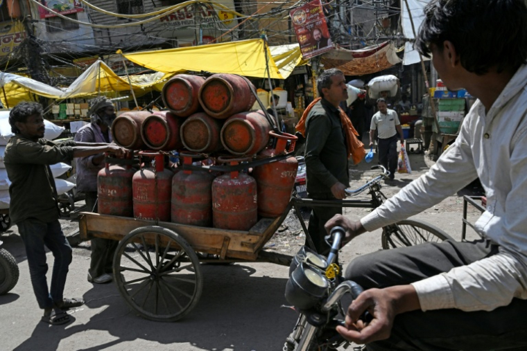 Des travailleurs transportent du gaz naturel liquéfié (GNL) en bonbonnes dans les rues de Delhi, le 10 avril 2026 ( AFP / Arun SANKAR )