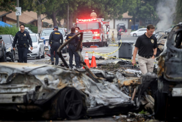 Des policiers et enquêteurs sur le site où s'est écrasé un avion privé, dans un quartier résidentiel de San Diego, en Californie, le 22 mai 2025 ( AFP / Sandy Huffaker )