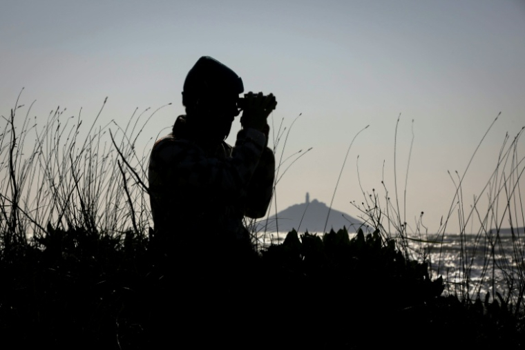 Sean Ronayne observe des oiseaux avec ses jumelles, sur la plage de Ballycotton, près de Cobh, le 3 avril 2025 ( AFP / Paul Faith )