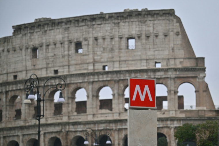 Cette photographie montre une vue de l'entrée de la nouvelle station de métro "Colosseo", conçue comme un musée pour présenter les découvertes archéologiques mises au jour lors de sa construction, alors qu'elle ouvre au public, avec le Colisée en arrière-plan, à Rome, le 16 décembre 2025. ( AFP / Filippo MONTEFORTE )