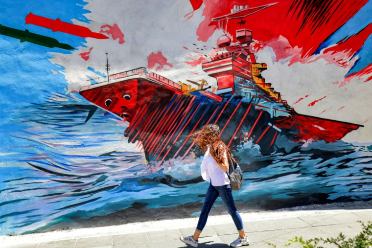 Une femme passe devant une peinture murale anti-américaine et anti-israélienne, le 26 mai 2026 à Téhéran ( AFP / ATTA KENARE )