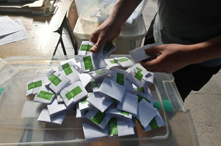 Un homme compte les bulletins dans un bureau de vote lors des élections générales, à Santiago, le 16 novembre 2025 ( AFP / Victor RUIZ )