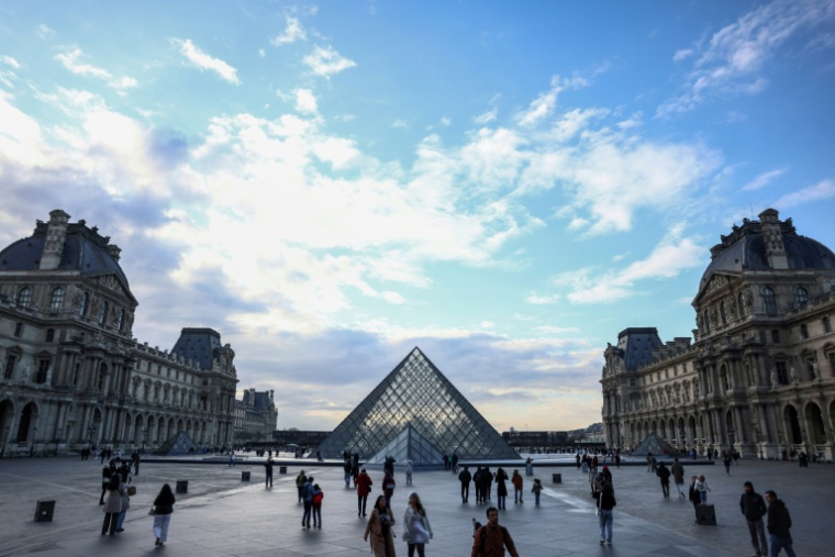 Des touristes près de la pyramide du Louvre, conçue par l'architecte sino-américain Ieoh Ming Pei, le 28 février 2025 ( AFP / Behrouz MEHRI )