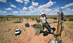 Cole Garcia, ouvrier de l'entreprise Mohave Electric, travaille sur un poteau électrique pour raccorder les maisons d'Amérindiens Navajo à Tonalea, en Arizona, le 8 juillet 2025 ( AFP / Frederic J. BROWN )