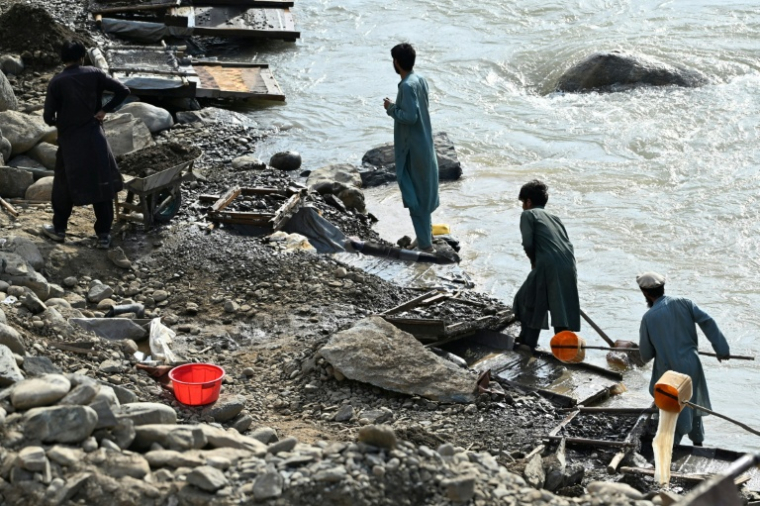 Des hommes versent de l'eau sur des tamis à la recherche de pépites d'or le long de la rivière Kunar, dans le district de Ghaziabad de la province de Kunar, le 13 avril 2026 en Afghanistan ( AFP / Wakil KOHSAR )