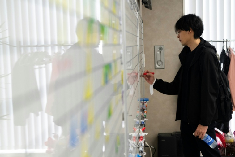 Un employé inscrit les objectifs quotidiens sur un tableau blanc dans les bureaux de Global Partners à Tokyo, le 1er juin 2026 au Japon ( AFP / Andrew CABALLERO-REYNOLDS )