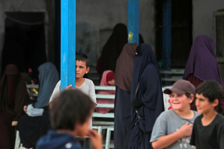Des femmes et enfants se tiennent devant un magasin dans le camp de Roj, construit pour accueillir des proches de personnes soupçonnées d’être des jihadistes, dans le nord-est de la Syrie, le 5 octobre 2026 ( AFP / Delil SOULEIMAN )