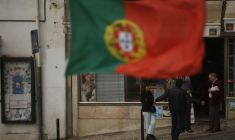 Des personnes discutent près d'un drapeau portugais dans le centre de Lisbonne