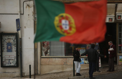 Des personnes discutent près d'un drapeau portugais dans le centre de Lisbonne