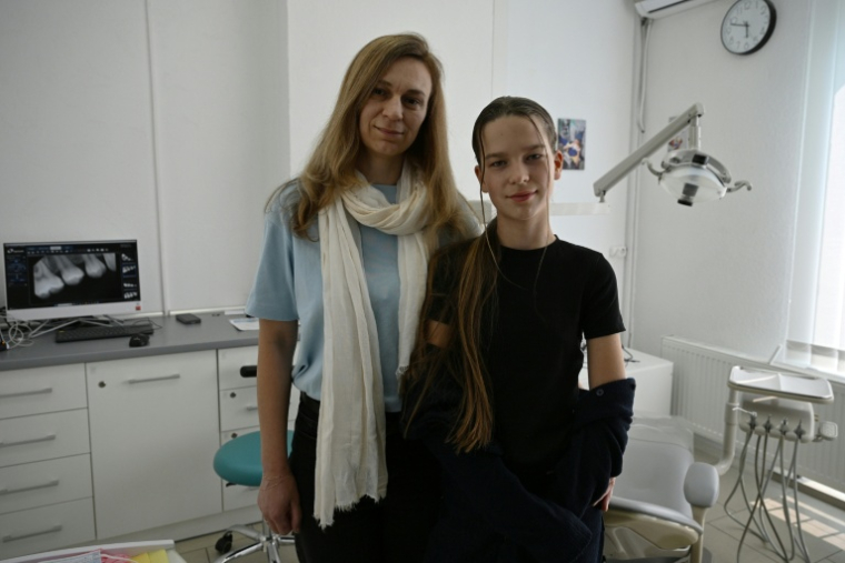 Les réfugiées ukrainiennes Iana Sidko et sa fille Daryna posent dans un clinique dentaire pour enfants à Kiev, en Ukraine, le 30 avril 2026  ( AFP / Genya SAVILOV )
