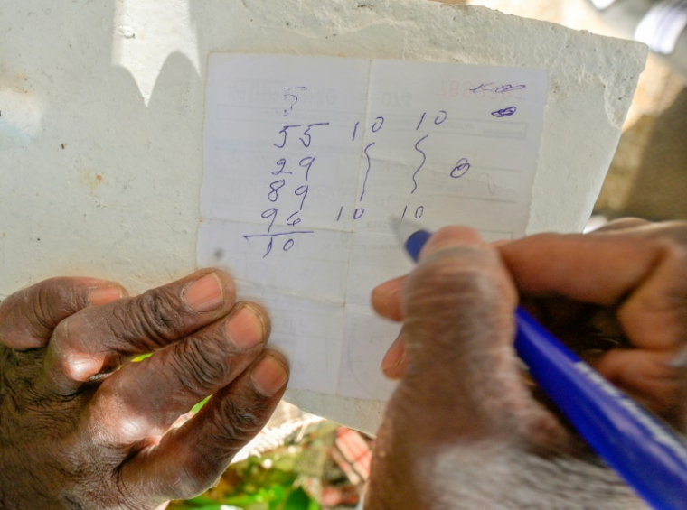 Un Cubain montre sur un bout de papier les numéros qu'il va jouer à la "bolita", la loterie clandestine, à La Havane, le 14 avril 2025 ( AFP / ADALBERTO ROQUE )