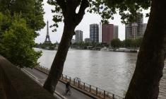 Un homme roule à vélo sur les rives de la Seine avec la Tour Eiffel en arrière-plan
