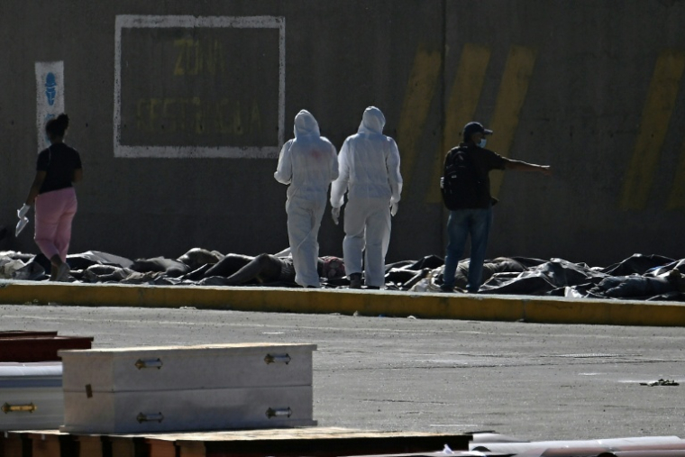 Des experts médicolégaux procèdent à l'identification de corps étendus au sol dans une morgue de fortune située dans le port de La Guaira, au Venezuela, le 29 juin 2026 ( AFP / Federico PARRA )