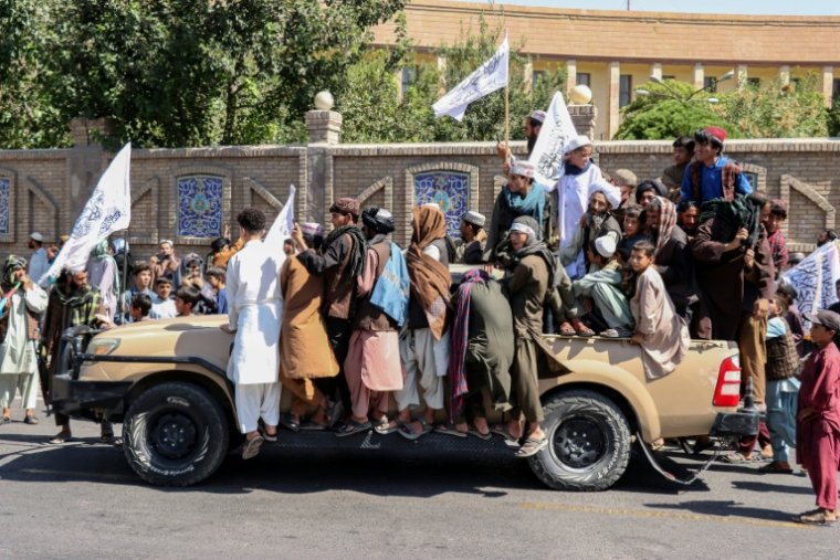 Des Afghans sur un véhicule des membres des forces de sécurité talibanes lors des célébrations du cinquième anniversaire de leur retour au pouvoir à Kaboul, le 15 août 2026 ( AFP / Mohsen KARIMI )