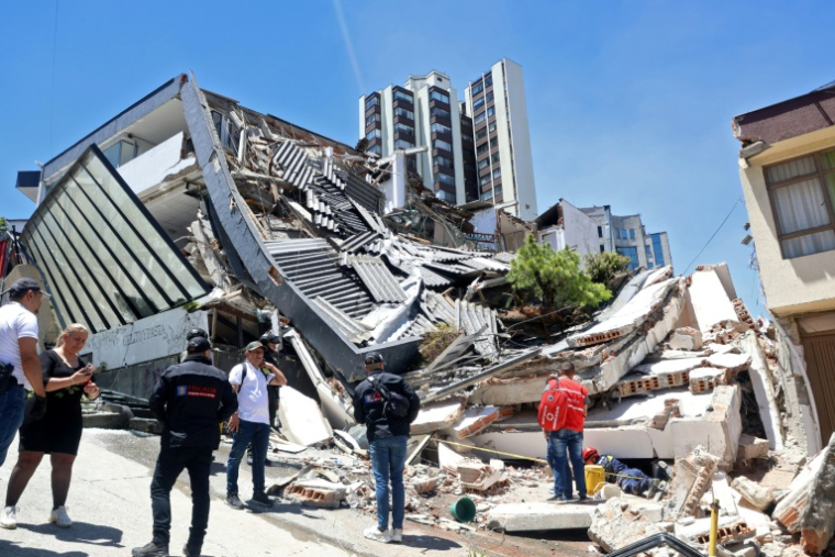 Des personnes se tiennent près d'un amas de débris après un puissant tremblement de terre à Manizales en Colombie, le 10 août 2026 ( AFP / Giovanny Galvez )