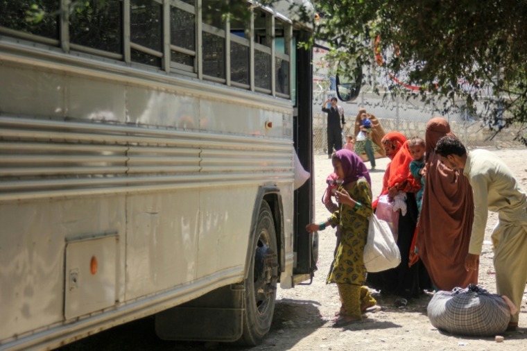Des rapatriés afghans montent dans un bus à leur arrivée du Pakistan, près du poste-frontière de Torkham, le 24 juin 2026 ( AFP / Aimal ZAHIR )