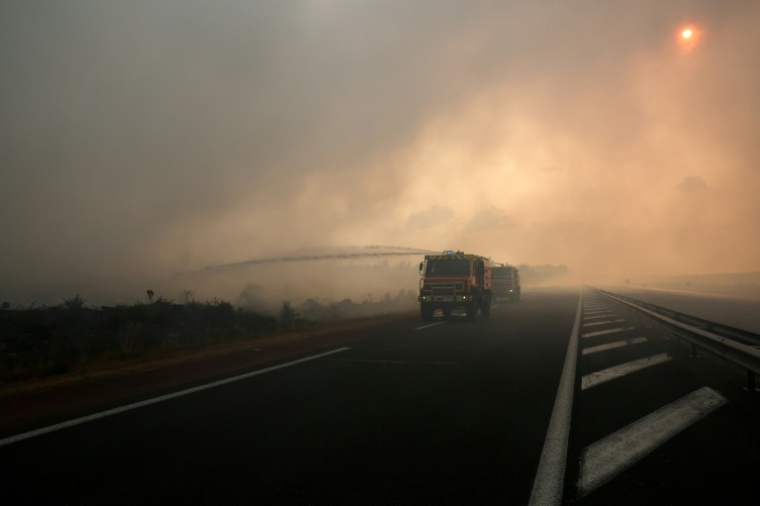 Un camion de pompiers en action en lisière de route, le 26 juillet 2026 à Arès, en Gironde ( AFP / ROMAIN PERROCHEAU )