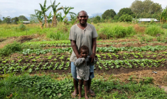 Dennis Phillip et son fils Kayddy dans leur potager où des dizaines de bombes américaines non explosées de la Seconde Guerre mondiale ont été retrouvées, le 11 septembre 2025 à Honiara, aux Iles Salomon ( AFP / Ben STRANG )