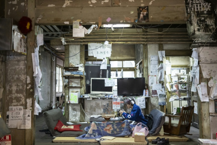 Un résident du Foyer Yoshida de l'Université de Kyoto examine un générateur électrique dans le hall d'entrée, le 3 févroer 2026 au Japon ( AFP / Yuichi YAMAZAKI )