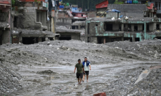 Des habitants traversent, le 30 août 2026, une rue ensevelie sous des tonnes de boue du centre de Trishuli, au Népal, victime d'une crue dévastatrice ( AFP / Arun SANKAR )