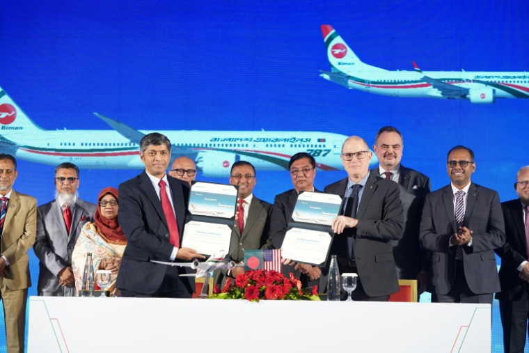 Photo diffusée par Biman Bangladesh Airlines montrant le PDG de compagnie aérienne, Kaizer Sohel Ahmed (g), et le vice-président de Boeing, Paul Righi (d), échangeant des documents après la signature d'un accord à Dacca, le 30 avril 2026 au Bangladesh ( Biman Bangladesh Airlines  / Handout )