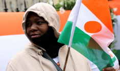 Une personne tient un drapeau du Niger devant l'ambassade du Niger, à Paris