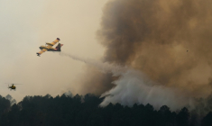 Vue prise depuis un hélicoptère de la Sécurité civile montrant un Canadair larguant de l'eau sur un incendie à Saint-Jean-d'Illac, en Gironde, le 28 juillet 2026 ( POOL / Baz Ratner )