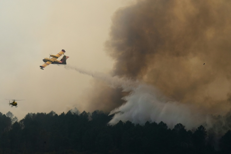 Vue prise depuis un hélicoptère de la Sécurité civile montrant un Canadair larguant de l'eau sur un incendie à Saint-Jean-d'Illac, en Gironde, le 28 juillet 2026 ( POOL / Baz Ratner )