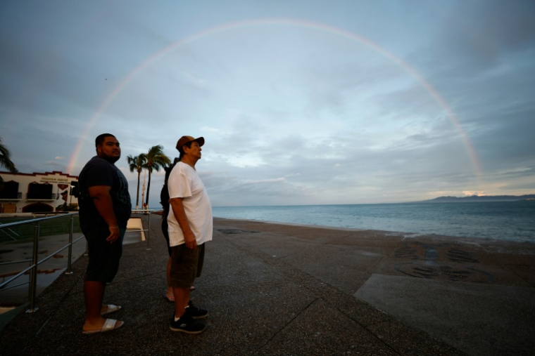 Des personnes se tiennent le long d’une promenade sous un arc-en-ciel à Puerto Vallarta, au Mexique, le 12 octobre 2026 ( AFP / ULISES RUIZ )