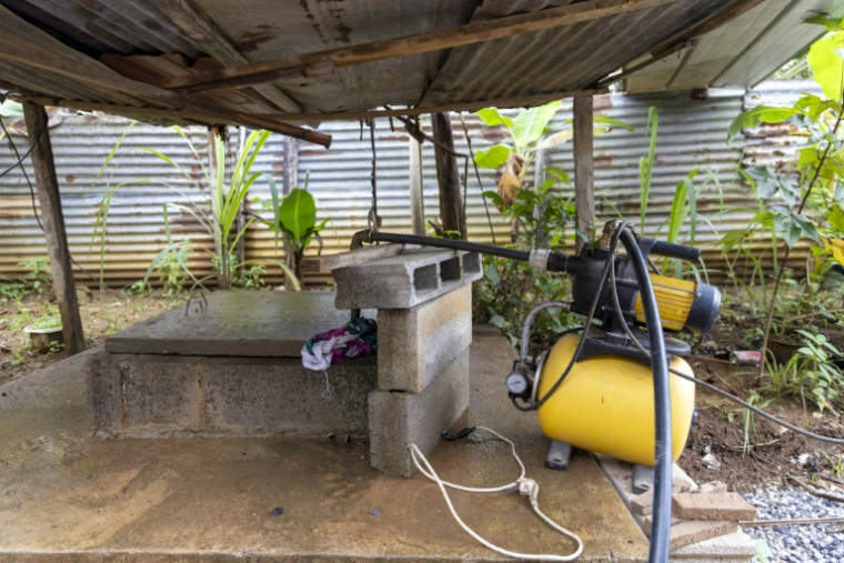 Un puits creusé près d'une maison et la pompe électrique qui permet de tirer l'eau, le 6 juin 2026 à Savane, un quartier de Matoury, en périphérie de Cayenne ( AFP / Ronan LIÉTAR )